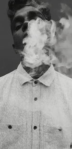 Close-up of man smoking against black background