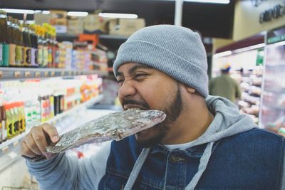 Close-up portrait of man biting frozen fish