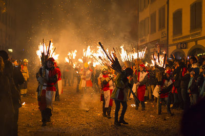 Chienbaese festival. switzerland, liestal, feb 18. participants carrying burning logs through town.