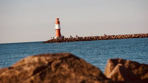 Lighthouse by sea against sky