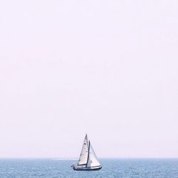 Boat sailing in sea against clear sky