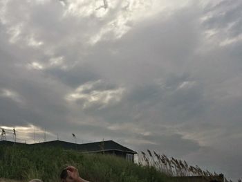 Man standing by building against sky