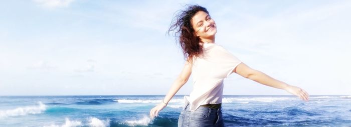 Beautiful woman standing in sea against sky