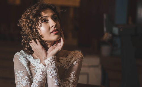 Thoughtful woman in wedding dress sitting with head in hands at home