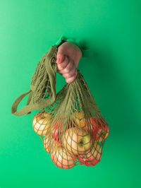 Close-up of hand holding leaf against blue background