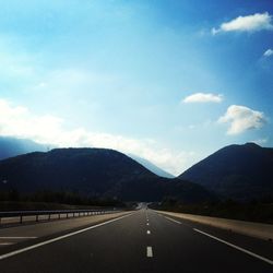 Empty road by mountains against sky