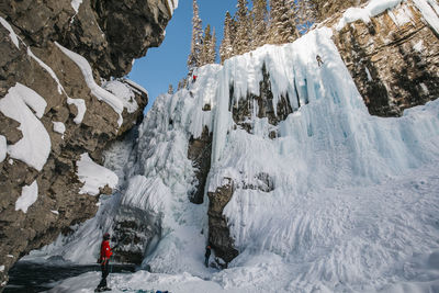 Side view of man with rope standing on snowcapped mountain