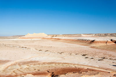 Scenic view of desert against clear blue sky