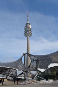 Communications tower in city against sky