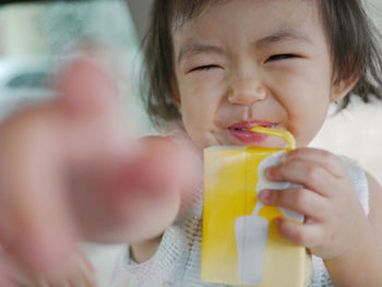 Close-up portrait of cute baby drinking milk while making face