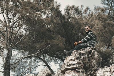 Low angle view of man sitting on rock