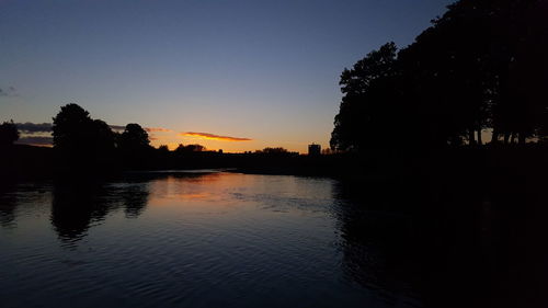 Scenic view of silhouette trees against clear sky during sunset