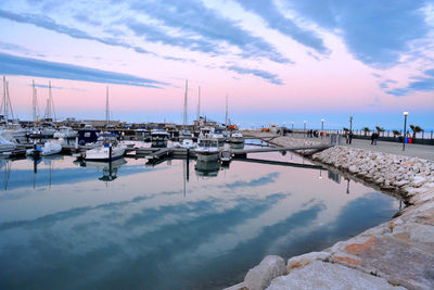 Sailboats moored at harbor against sky