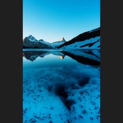 Scenic view of frozen lake by mountain against sky