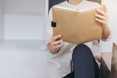 Midsection of woman reading book