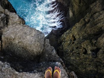 Low section of person standing on rock at beach