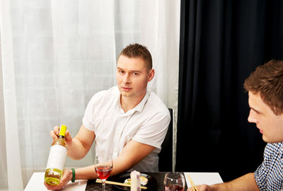 Young man looking away while sitting on table