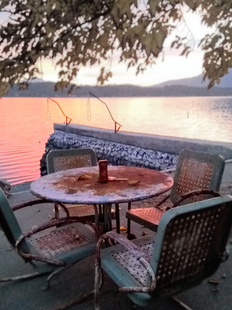 EMPTY CHAIRS AND TABLE ON BEACH AGAINST SKY