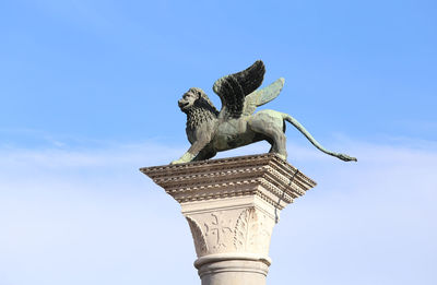 Lion wings of st. mark on a marble pedestal with a blue sky