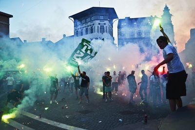 Football supporters celebrating with fire crackers on road