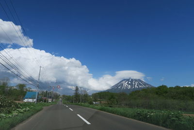 Diminishing perspective of road against blue sky during sunny day