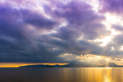 Scenic view of sea against dramatic sky during sunset