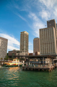 Modern buildings by river against sky in city