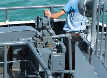 Midsection of engineer standing by machinery on boat