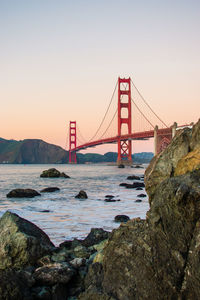 Suspension bridge over sea against clear sky