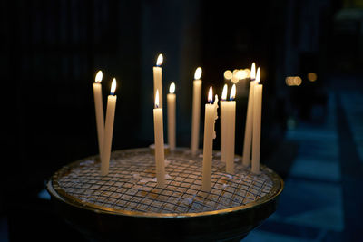 Close-up of illuminated candles on table in temple