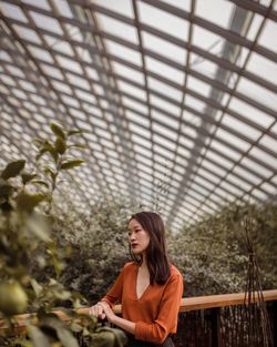 Portrait of young woman standing in greenhouse