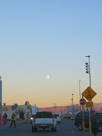 Road sign on street against clear sky during sunset