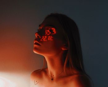 Close-up portrait of a young woman against wall