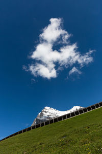 Tilt image of hill and snowcapped mountain against sky