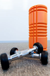 Close-up of foam roller and dumbbells on floor