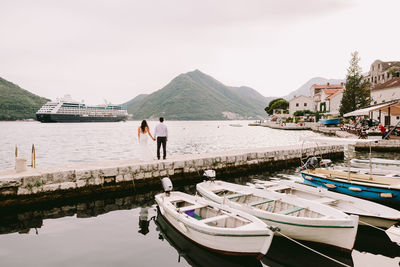 Rear view of couple standing by lake against sky