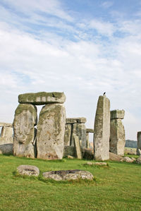 Stonehenge on grassy field against cloudy sky
