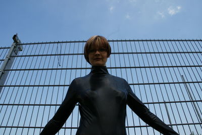 Low angle view of woman standing against fence