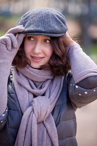 Beautiful woman holding cap while looking away in park