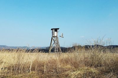 Water tower on field against clear blue sky