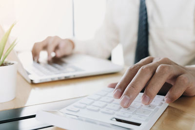 Midsection of man using laptop on table