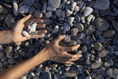 Woman hands touching stones on the beach. grey stones