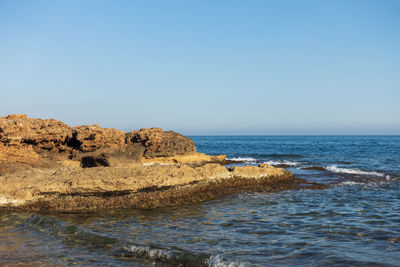 Rocks on beach against clear sky