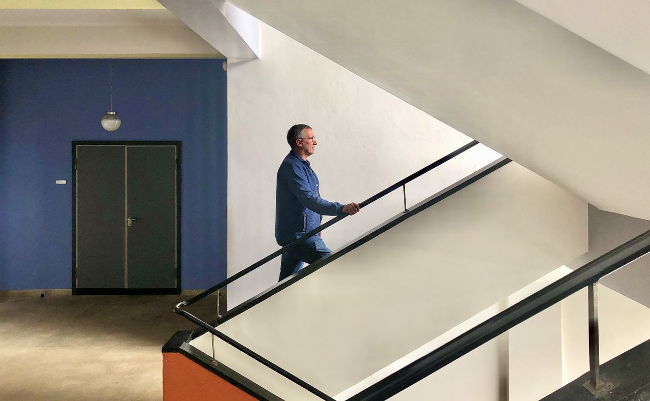 SIDE VIEW OF MAN STANDING ON STAIRCASE IN BUILDING
