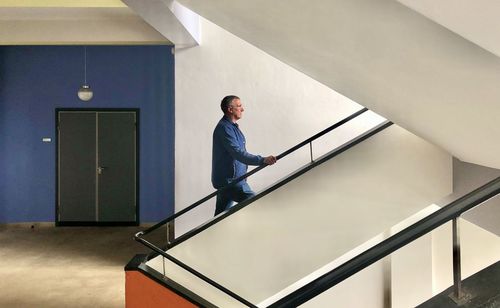 Side view of young man standing on staircase in building