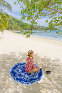 Woman sitting on beach by sea