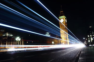 Light trails on road by big ben at night