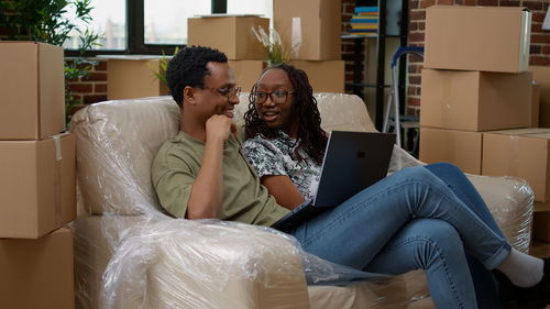 Couple using phone while sitting on sofa at home