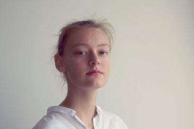 Close-up portrait of confident young woman standing against white background