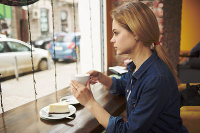 Side view of young woman drinking coffee at cafe